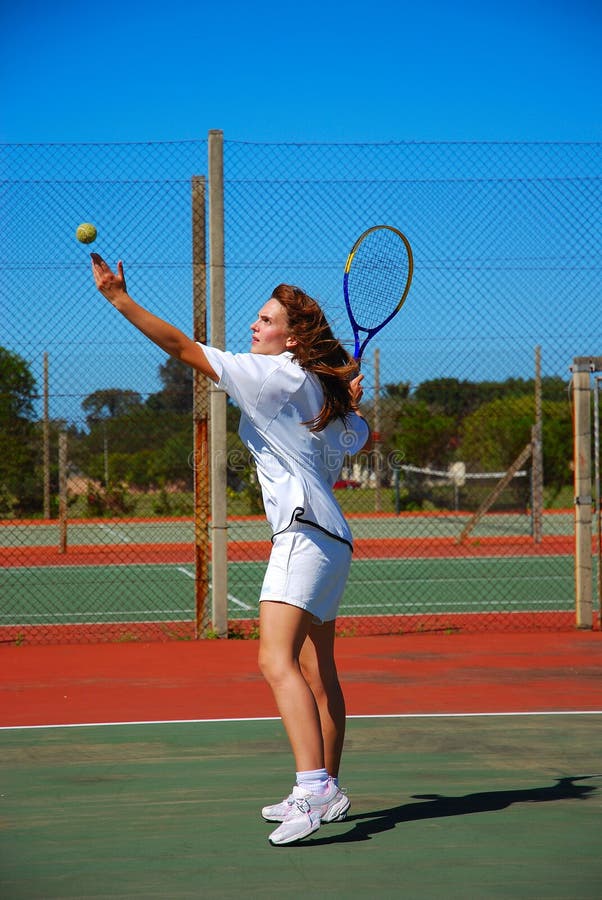 Full body of a beautiful caucasian white teenage girl with concentrating facial expression, focusing on hitting the ball, during summer training on the tennis court outdoors. Full body of a beautiful caucasian white teenage girl with concentrating facial expression, focusing on hitting the ball, during summer training on the tennis court outdoors.