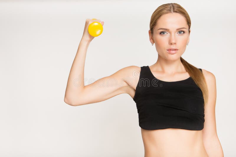 Muchacha deportiva que hace ejercicio con pesas de gimnasia y que mira la cámara imagenes de archivo Muchacha deportiva que hace ejercicio con pesas de gimnasia y que mira la cámara imagenes de archivo