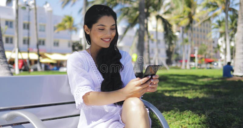 Muchacha elegante confiada que usa el teléfono en parque