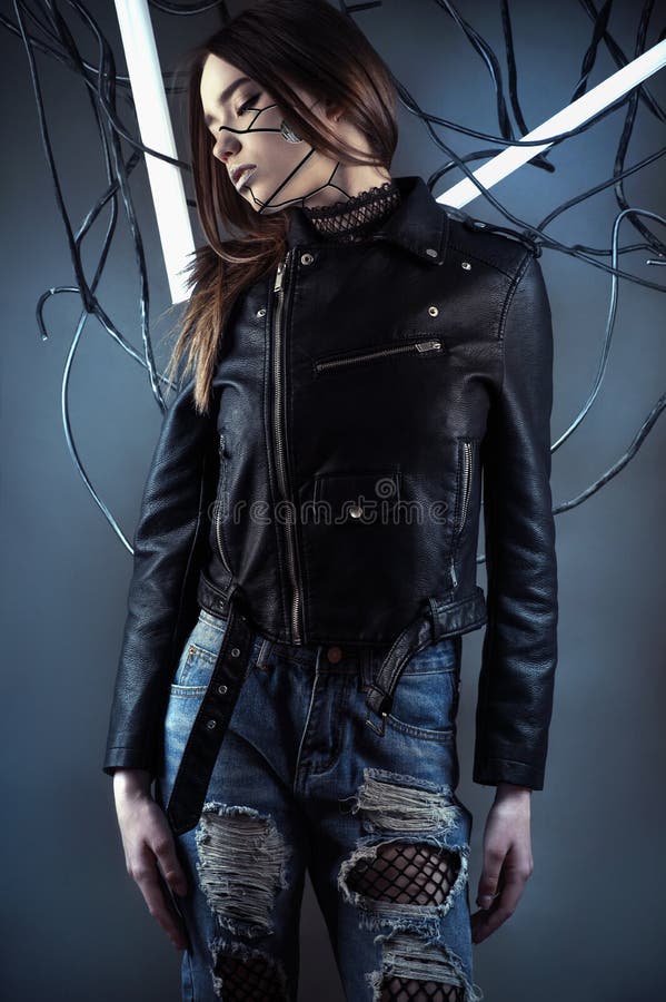 Elegant robot girl in wires in style cyberpunk in leather jacket and ripped jeans in studio shot. Elegant robot girl in wires in style cyberpunk in leather jacket and ripped jeans in studio shot