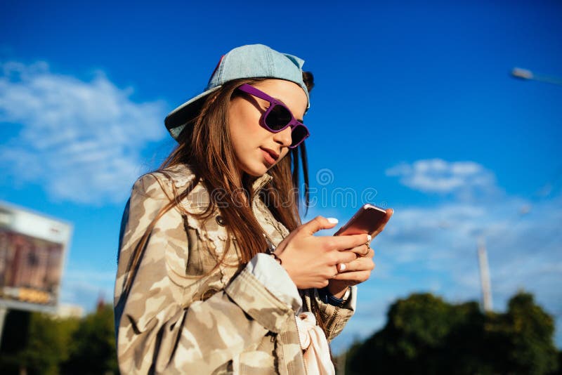 Muchacha elegante que usa un smartphone, al aire libre fotografía de archivo Muchacha elegante que usa un smartphone, al aire libre fotografía de archivo