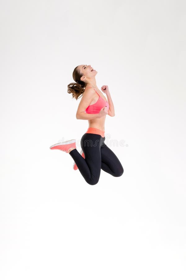 Muchacha emocionada atractiva de la aptitud en el salto del sportwear de la alegría imágenes de archivo libres de regalías Muchacha emocionada atractiva de la aptitud en el salto del sportwear de la alegría imágenes de archivo libres de regalías