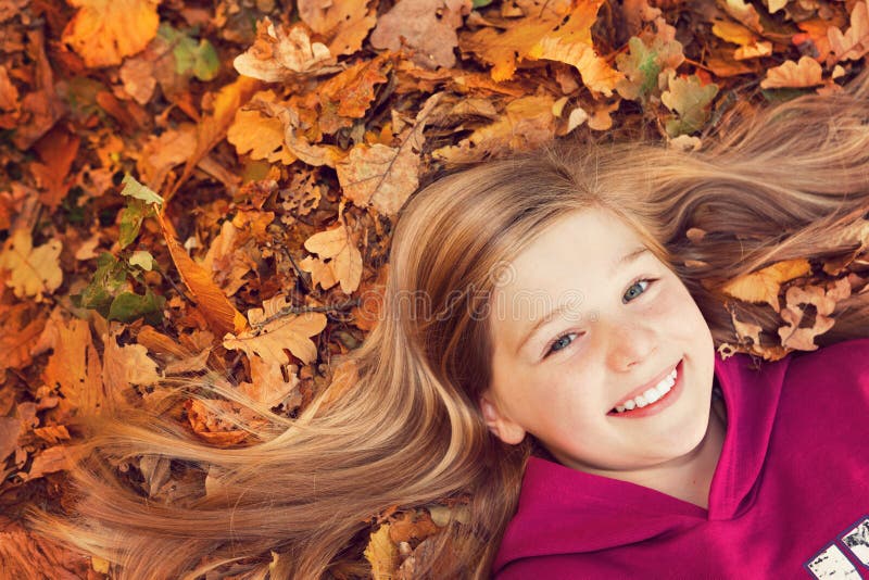 Muchacha en la sonrisa de las hojas de otoño foto de archivo libre de regalías Muchacha en la sonrisa de las hojas de otoño foto de archivo libre de regalías