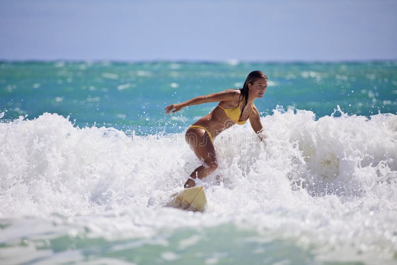 Muchacha en un bikiní amarillo que practica surf