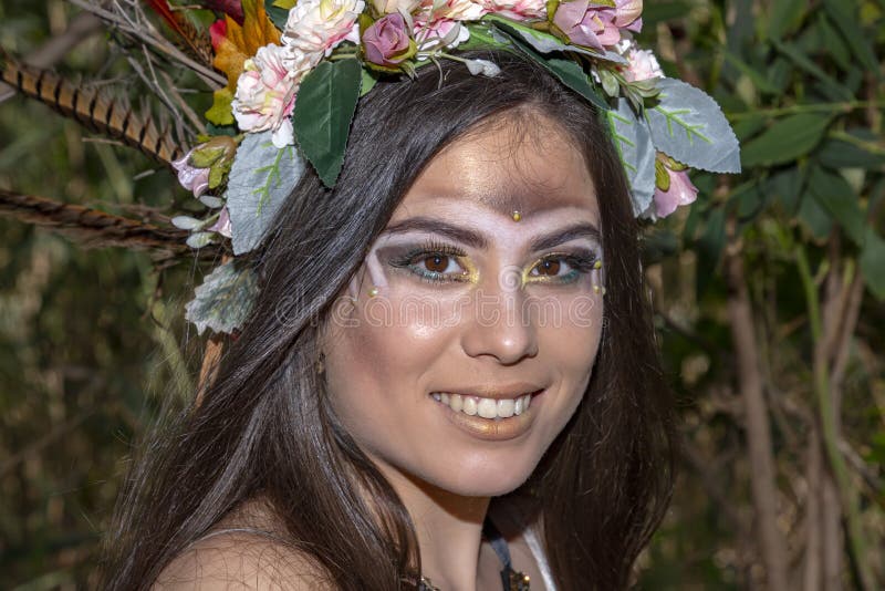 Muchacha en un tocado del nativo americano contra la perspectiva del follaje verde imagen de archivo libre de regalías Muchacha en un tocado del nativo americano contra la perspectiva del follaje verde imagen de archivo libre de regalías