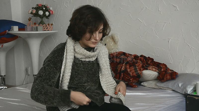 Muchacha enferma en un suéter con un termómetro a disposición metrajes
