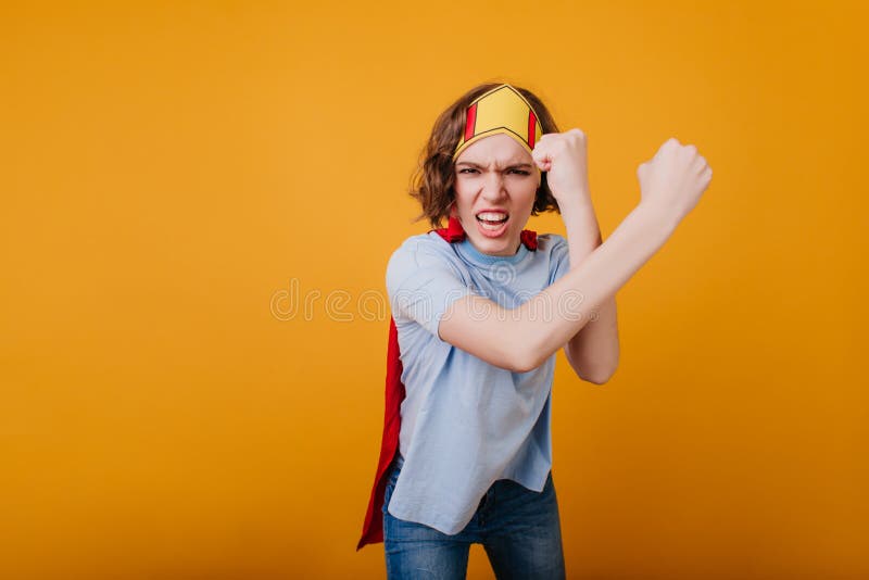 Muchacha enojada con la corona de juguete posando en un fondo amarillo. toma de estudio de una mujer con el acorazado lista para luchar.