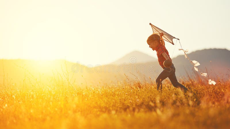 Muchacha feliz del niño con una cometa que corre en prado en verano