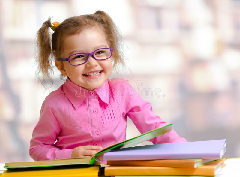 Muchacha feliz del niño en libro de lectura de las lentes fotos de archivo libres de regalías Muchacha feliz del niño en libro de lectura de las lentes fotos de archivo libres de regalías