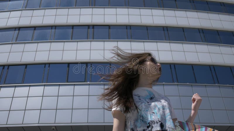 Muchacha feliz en una calle de la ciudad con los paquetes y las compras