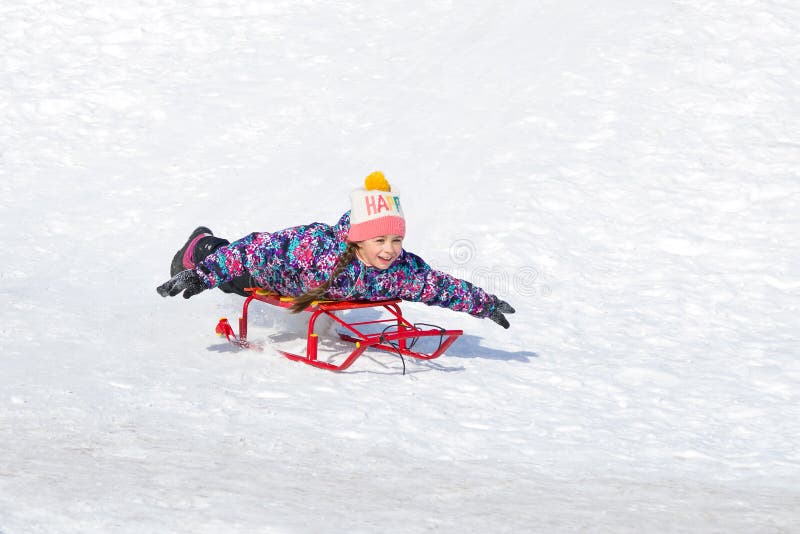 Muchacha feliz linda en un trineo que resbala abajo de una colina en nieve imagenes de archivo Muchacha feliz linda en un trineo que resbala abajo de una colina en nieve imagenes de archivo