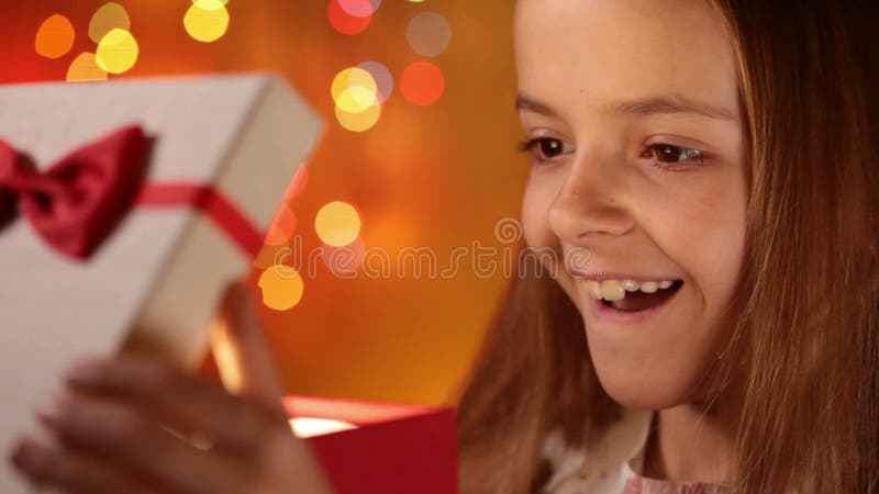 Muchacha feliz que abre su regalo de Navidad