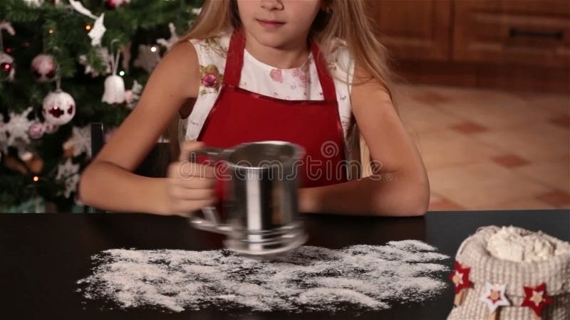 Muchacha feliz que escribe Navidad en la harina