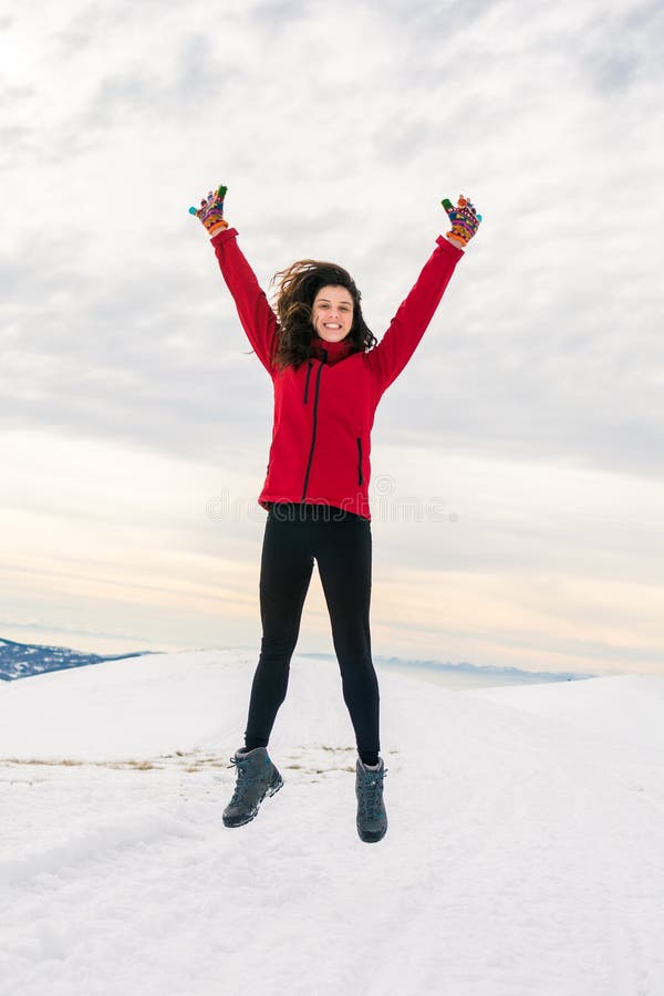 Muchacha feliz que salta en el top nevado de la montaña fotos de archivo Muchacha feliz que salta en el top nevado de la montaña fotos de archivo