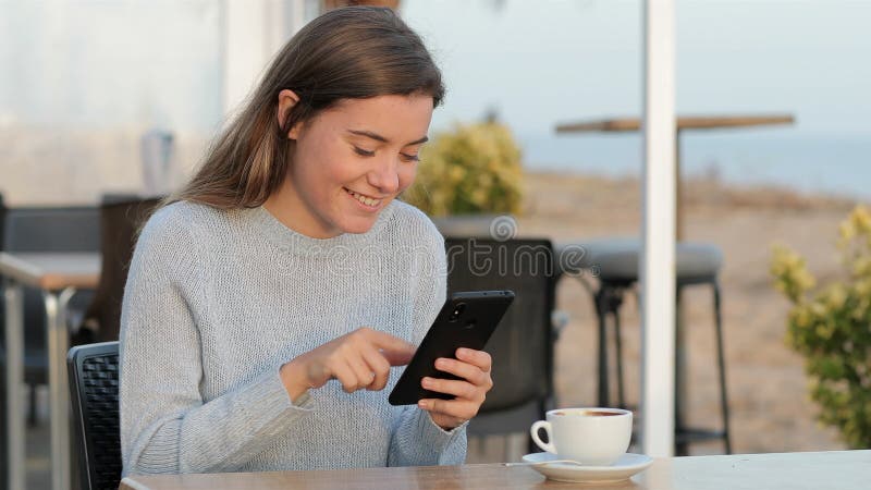 Muchacha feliz usando teléfono móvil en una cafetería