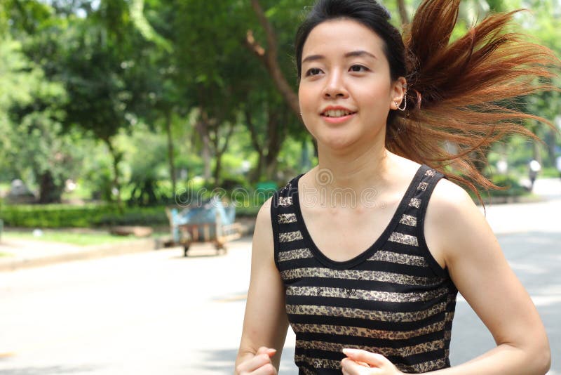 Muchacha hermosa adulta tailandesa que hace ejercicios corrientes en el parque fotos de archivo libres de regalías Muchacha hermosa adulta tailandesa que hace ejercicios corrientes en el parque fotos de archivo libres de regalías