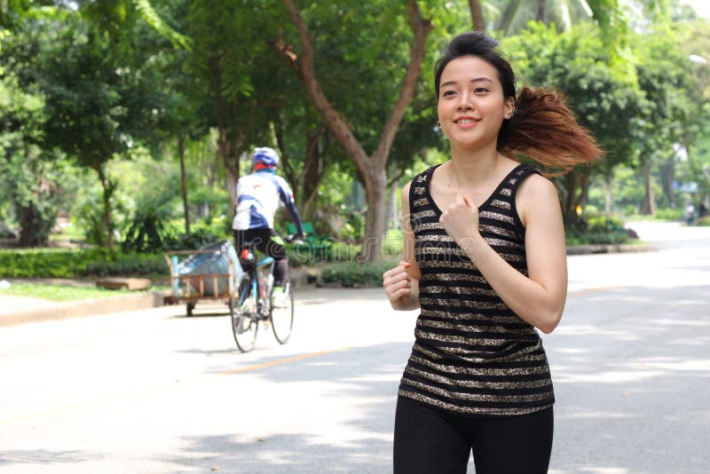 Muchacha hermosa adulta tailandesa que hace ejercicios corrientes en el parque fotos de archivo Muchacha hermosa adulta tailandesa que hace ejercicios corrientes en el parque fotos de archivo