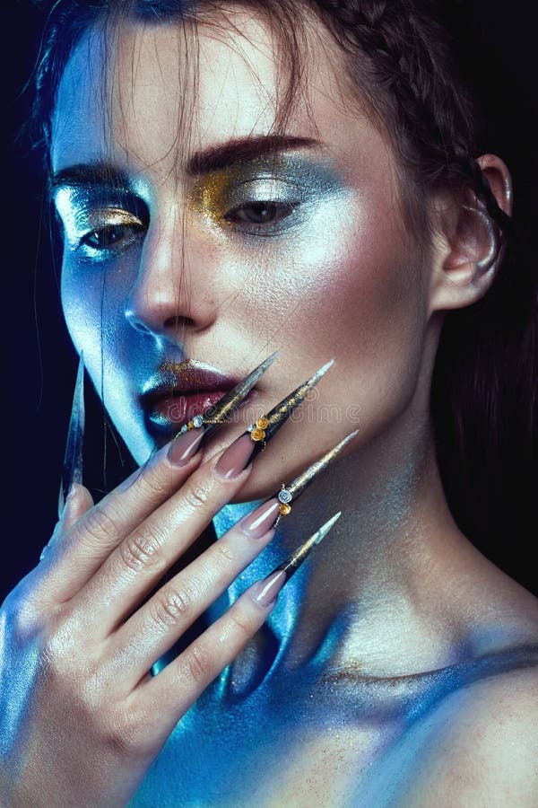 Muchacha hermosa con el maquillaje de oro y de plata creativo del brillo, arte largo de los clavos Cara de la belleza fotografía de archivo libre de regalías