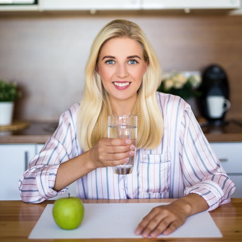 Muchacha hermosa con la manzana y vidrio de agua en cocina fotos de archivo Muchacha hermosa con la manzana y vidrio de agua en cocina fotos de archivo