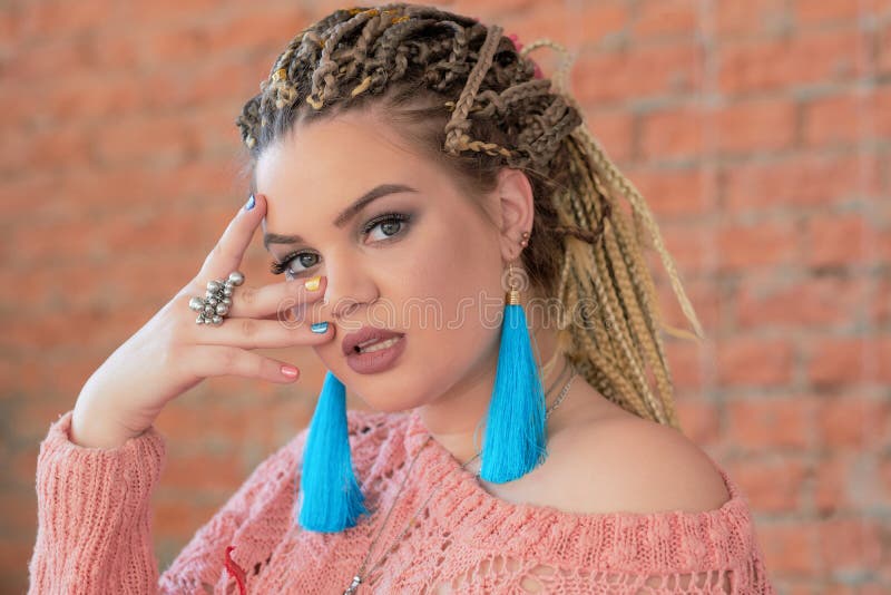 Muchacha hermosa del tamaño extra grande que miente en el sofá n un suéter rosado caliente y pendientes brillantes Estilo de Boho fotos de archivo libres de regalías Muchacha hermosa del tamaño extra grande que miente en el sofá n un suéter rosado caliente y pendientes brillantes Estilo de Boho fotos de archivo libres de regalías