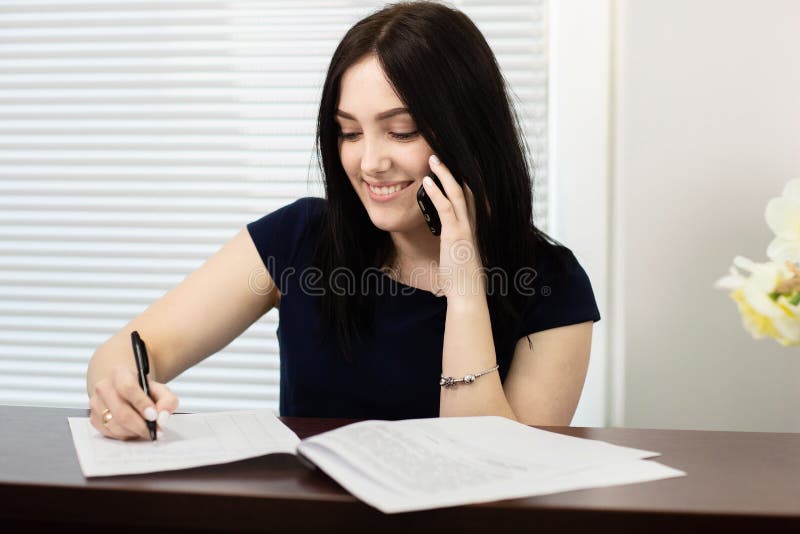Muchacha hermosa en el mostrador de recepci?n que contesta a la llamada en oficina dental fotografía de archivo libre de regalías Muchacha hermosa en el mostrador de recepci?n que contesta a la llamada en oficina dental fotografía de archivo libre de regalías