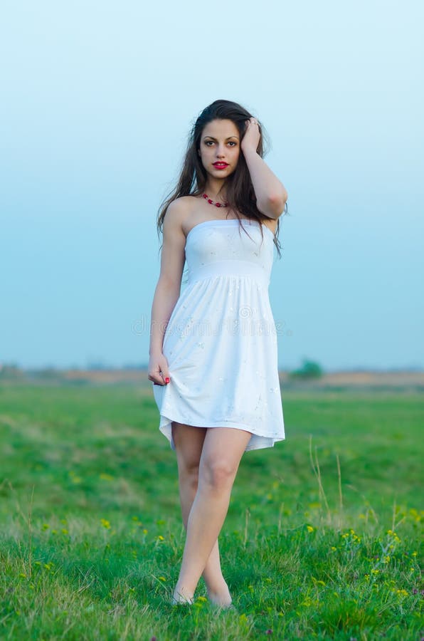 Muchacha hermosa en el vestido blanco que camina en prado de la primavera fotos de archivo libres de regalías Muchacha hermosa en el vestido blanco que camina en prado de la primavera fotos de archivo libres de regalías