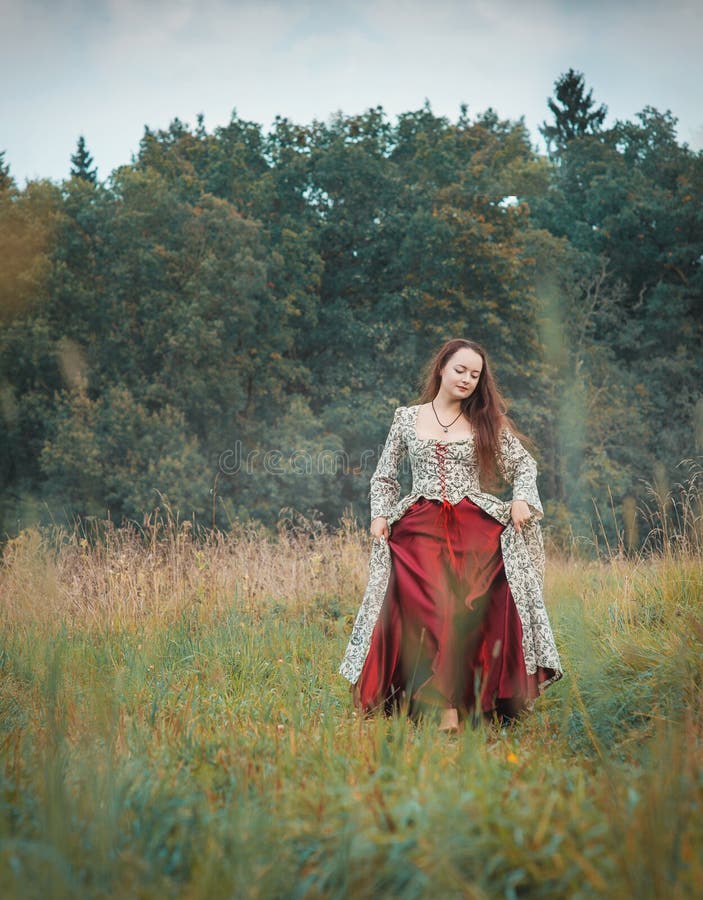 Muchacha hermosa en vestido medieval largo que camina en prado del verano fotos de archivo libres de regalías Muchacha hermosa en vestido medieval largo que camina en prado del verano fotos de archivo libres de regalías