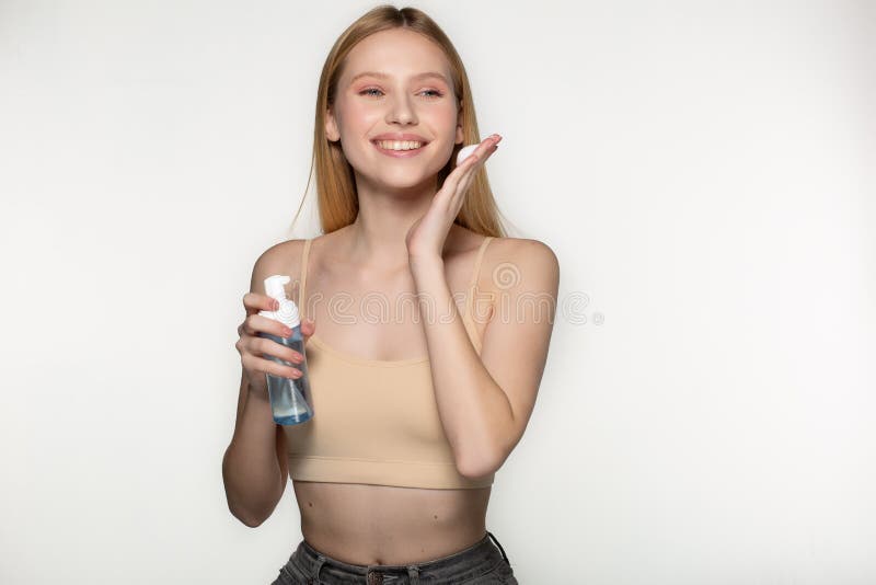 Muchacha hermosa feliz joven con la piel perfecta que aplica la crema cosm?tica en la cara aislada en fondo gris en el estudio imágenes de archivo libres de regalías Muchacha hermosa feliz joven con la piel perfecta que aplica la crema cosm?tica en la cara aislada en fondo gris en el estudio imágenes de archivo libres de regalías
