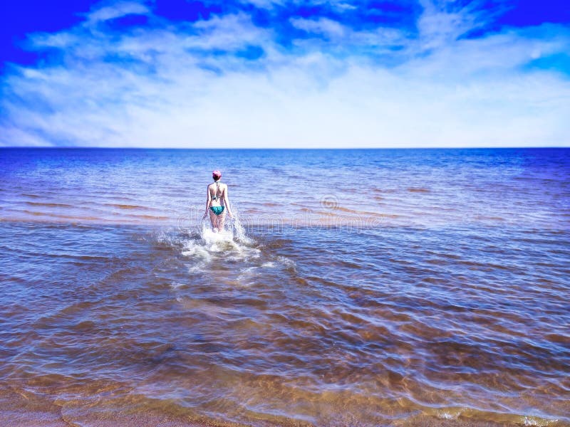 Muchacha hermosa que camina entre el agua brillante del mar azul imagen de archivo Muchacha hermosa que camina entre el agua brillante del mar azul imagen de archivo