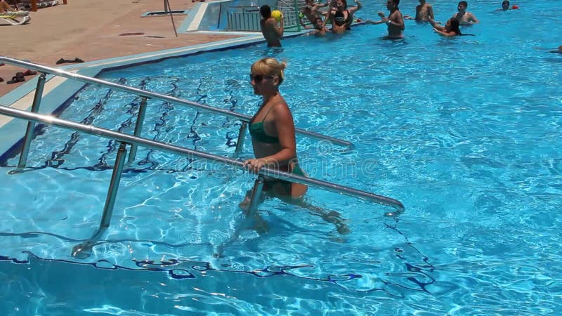 Muchacha hermosa que deja la piscina después de bañar Mujer joven que disfruta de días de fiesta tropicales almacen de video