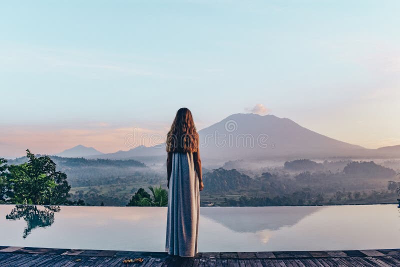 Muchacha hermosa que permanece la piscina cercana con el volcán fantástico fotografía de archivo Muchacha hermosa que permanece la piscina cercana con el volcán fantástico fotografía de archivo