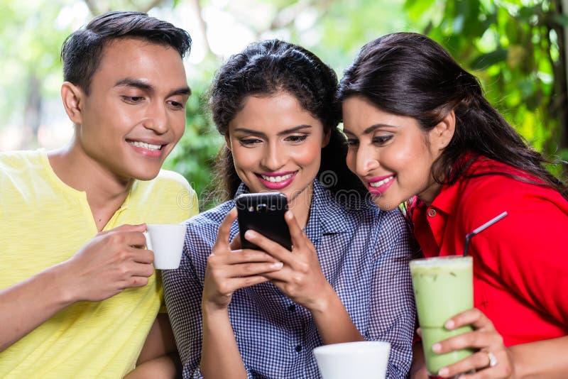 Muchacha india que muestra imágenes en el teléfono a los amigos imagen de archivo Muchacha india que muestra imágenes en el teléfono a los amigos imagen de archivo