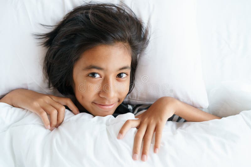 Muchacha linda asiática que despierta de sueño la mañana La cara de la niña es relajación después de despierta foto de archivo Muchacha linda asiática que despierta de sueño la mañana La cara de la niña es relajación después de despierta foto de archivo