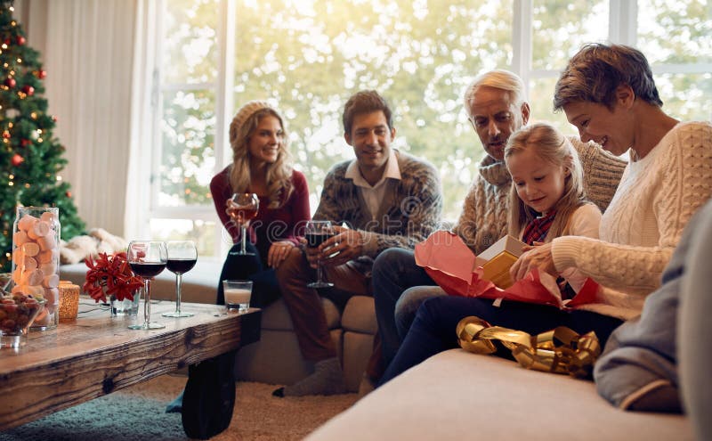 Muchacha linda con la familia y el regalo de Navidad de la abertura imagen de archivo Muchacha linda con la familia y el regalo de Navidad de la abertura imagen de archivo