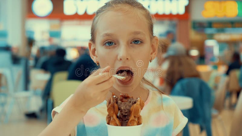Muchacha linda del adolescente que come el helado en zona de restaurantes Adolescente de la chica joven que goza del postre del h almacen de video