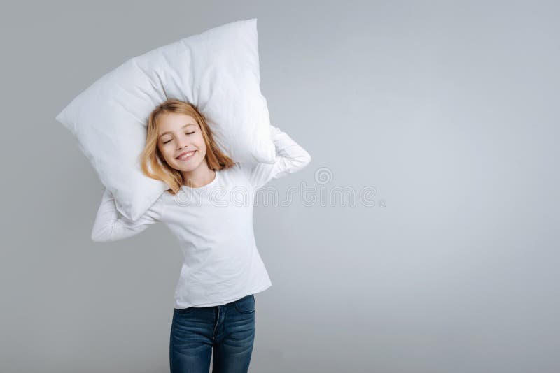 Muchacha linda sonriente que sostiene la almohada
