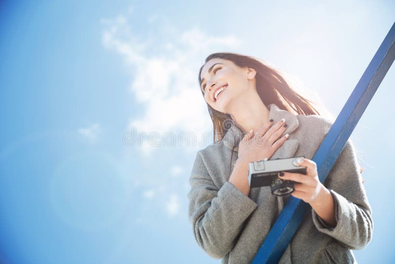 Muchacha morena bastante joven que parece ausente y que sostiene la cámara foto de archivo libre de regalías Muchacha morena bastante joven que parece ausente y que sostiene la cámara foto de archivo libre de regalías