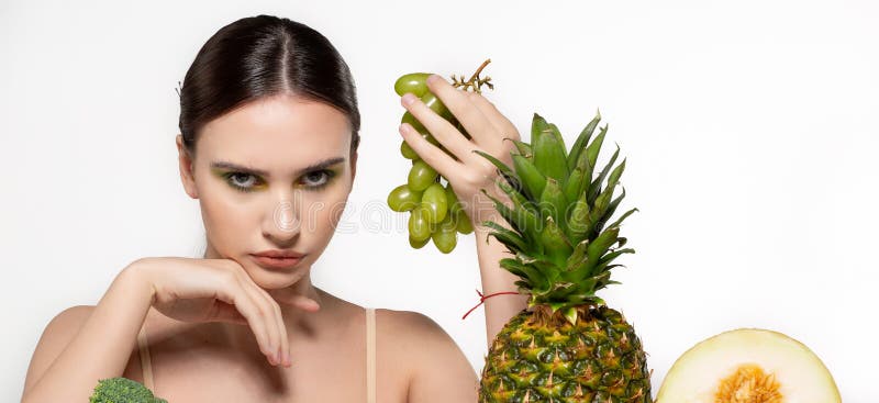 Muchacha morena hermosa con el maquillaje brillante que sostiene las uvas verdes a disposici?n, mirando la c?mara, frutas y verdu imagenes de archivo Muchacha morena hermosa con el maquillaje brillante que sostiene las uvas verdes a disposici?n, mirando la c?mara, frutas y verdu imagenes de archivo