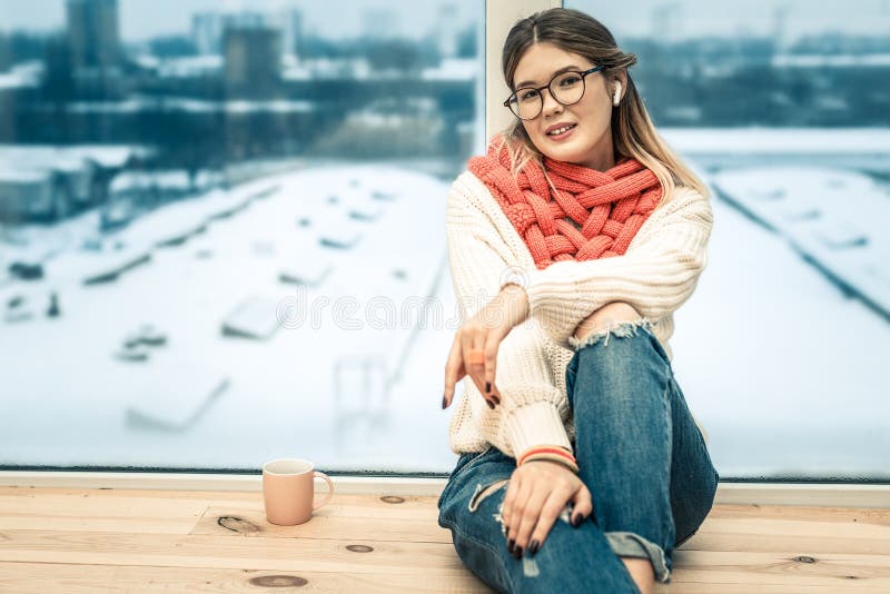 Muchacha pacífica coqueta que se inclina en ventana y que tiene calle del invierno en fondo foto de archivo Muchacha pacífica coqueta que se inclina en ventana y que tiene calle del invierno en fondo foto de archivo