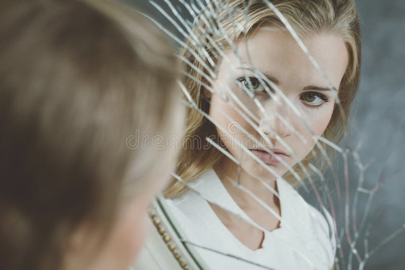 Teenage girl full of complexes looking at herself in the broken mirror. Teenage girl full of complexes looking at herself in the broken mirror