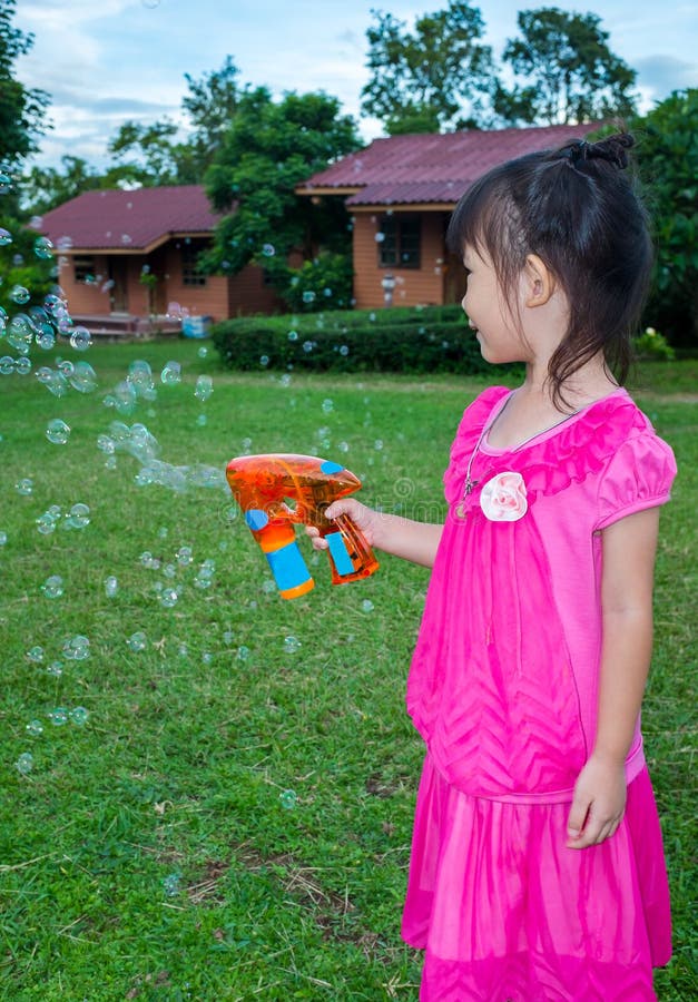 Muchacha preciosa asiática que juega en hierba verde en la yarda Al aire libre en su foto de archivo libre de regalías