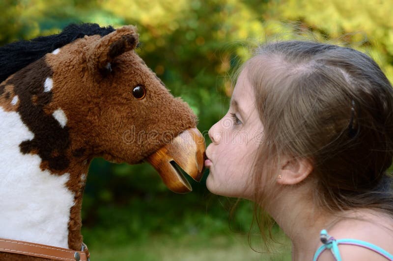Muchacha que besa un caballo mecedora imágenes de archivo libres de regalías Muchacha que besa un caballo mecedora imágenes de archivo libres de regalías