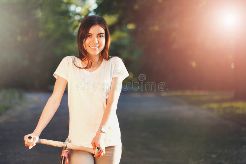Muchacha que camina con la bicicleta en la puesta del sol fotos de archivo Muchacha que camina con la bicicleta en la puesta del sol fotos de archivo