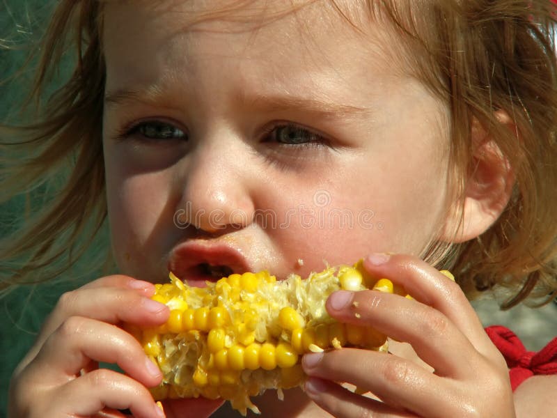 Muchacha que come el maíz en la mazorca