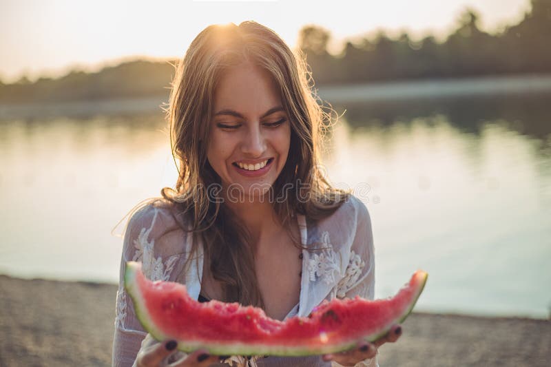 Muchacha que come la sandía y la sonrisa foto de archivo libre de regalías Muchacha que come la sandía y la sonrisa foto de archivo libre de regalías