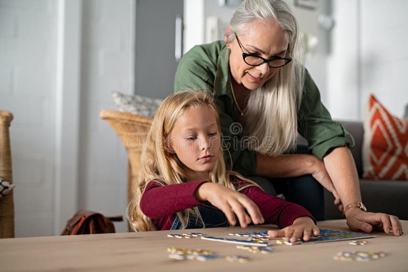 Muchacha que hace el rompecabezas con la abuela fotografía de archivo Muchacha que hace el rompecabezas con la abuela fotografía de archivo