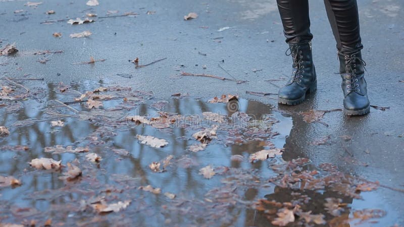 Muchacha que lleva las botas de combate negras que salpican en un charco después de lluvia metrajes