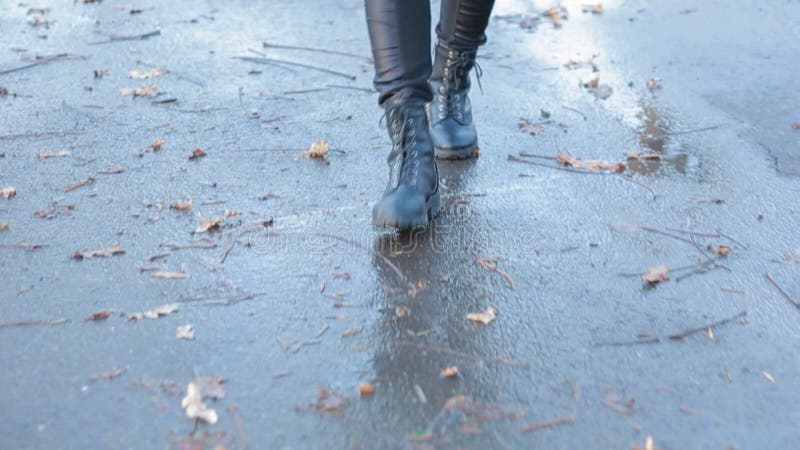 Muchacha que lleva las botas de combate negras que salpican en un charco después de lluvia metrajes