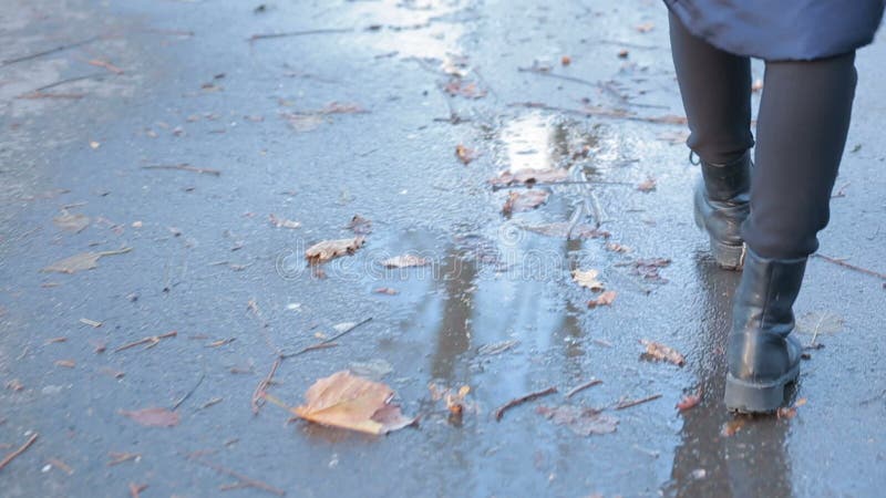 Muchacha que lleva las botas de combate negras que salpican en un charco después de lluvia almacen de video