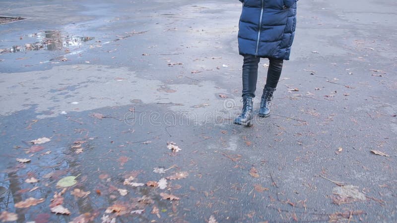 Muchacha que lleva las botas de combate negras que salpican en un charco después de lluvia metrajes